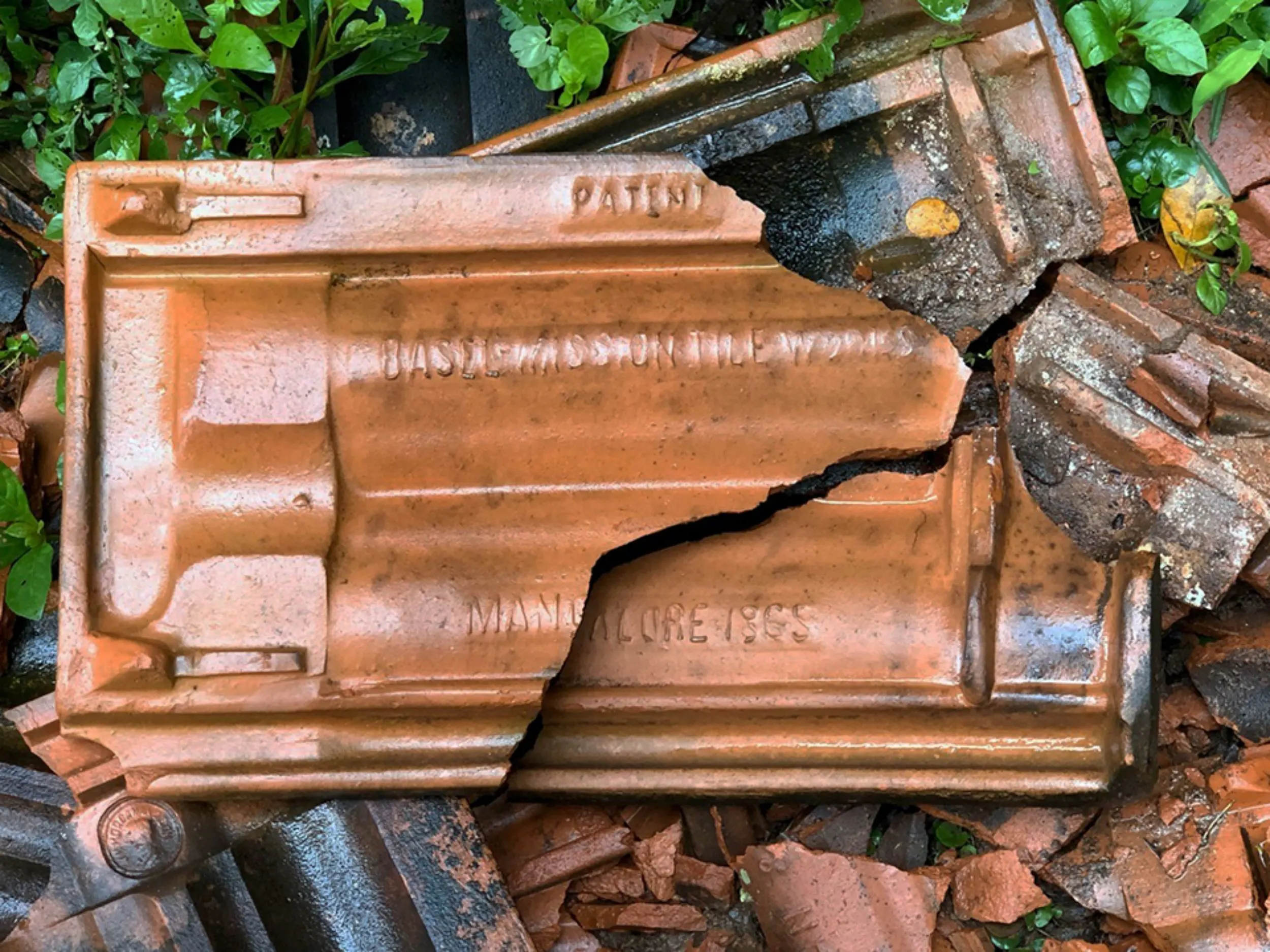 Ein in der Mitte durchgebrochener Ziegel mit der Aufschrift «PATENT BASEL MISSION TILE WORKS MANGALORE 1865»