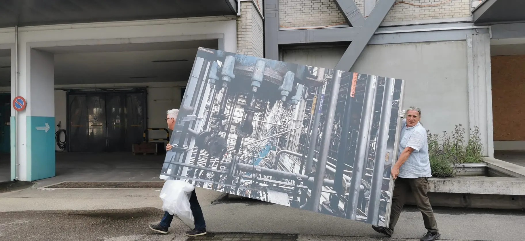 Zwei Personen tragen ein grosses Bild vom Chemiemuseum.